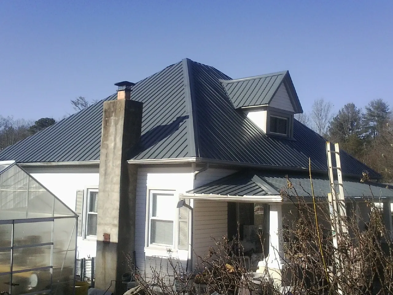 Dark blue standing seam metal roof on a white farmhouse with dormer — Slate & Tile Roof Repair by Roofing Brothers in Chualar