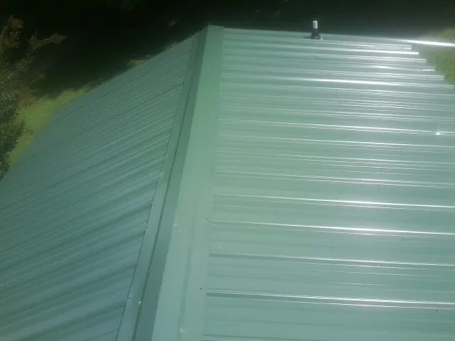 New green metal panels meeting at the ridge of a roof — Flat Roof Repair work by our crew in Chualar