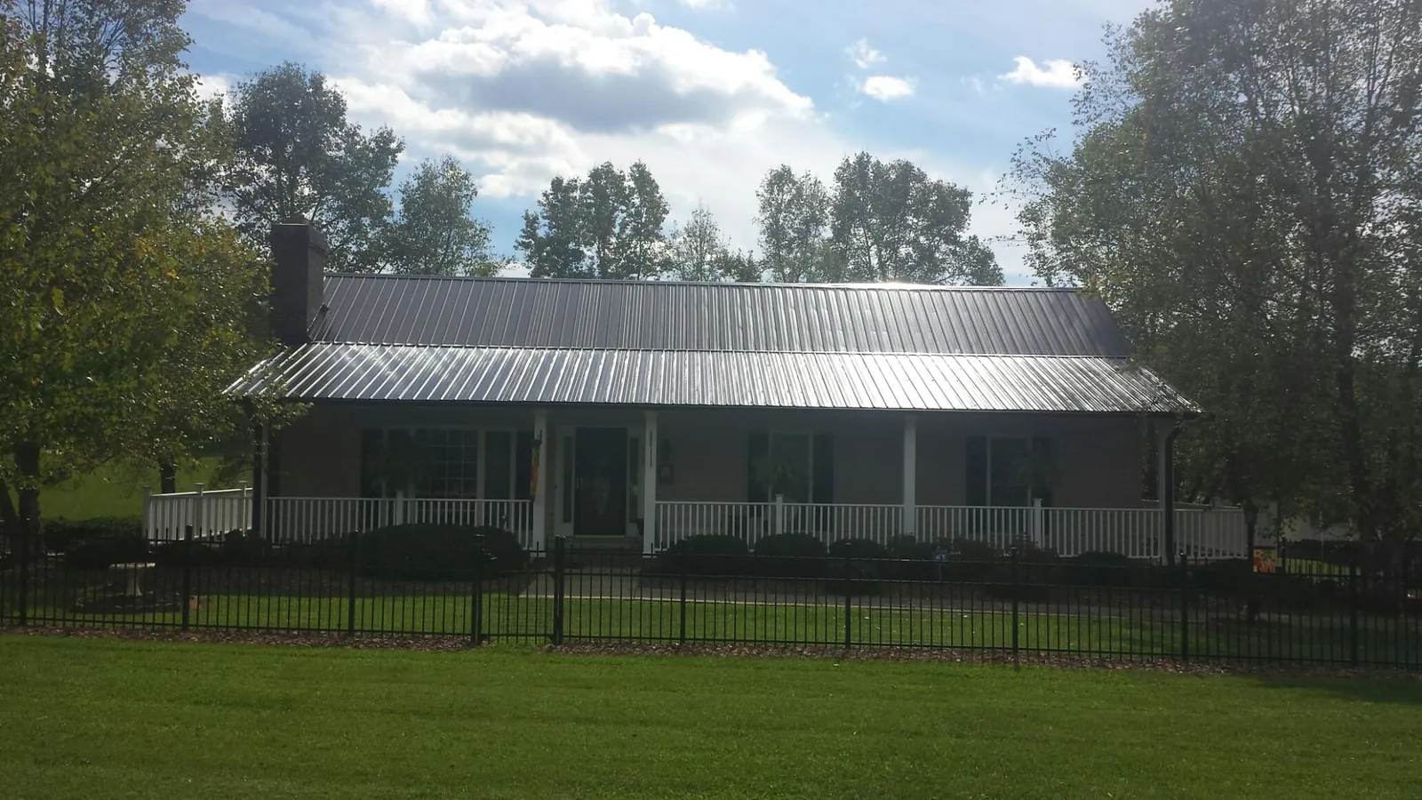 Gray metal roof on a brick ranch with a full width front porch — Gutter Guard Installation work by our crew in Chualar