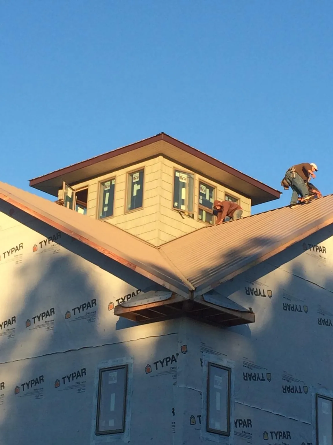 Roofers working around a rooftop cupola on a new metal roof at sunset — Roof Waterproofing in Chualar by Roofing Brothers